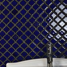 a white sink sitting next to a blue wall with an intricate design on it's side