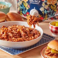 a bowl of chili with a spoon in it and some other food on the table