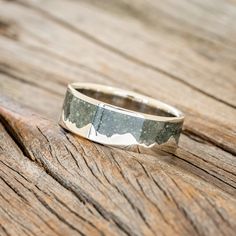 a silver ring sitting on top of a wooden table next to a piece of wood