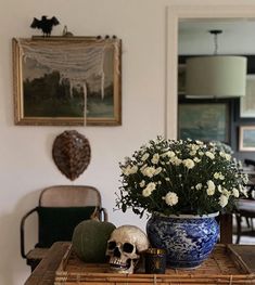 a table with a vase filled with flowers on top of it next to a skull