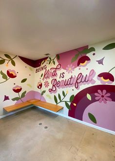 an empty room with flowers painted on the wall and bench in front of it that says being kind is beautiful