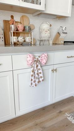 a kitchen with white cabinets and pink bows hanging from the front door, on top of a wooden floor