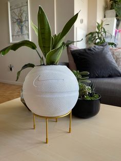 a white ball shaped planter sitting on top of a table next to a couch