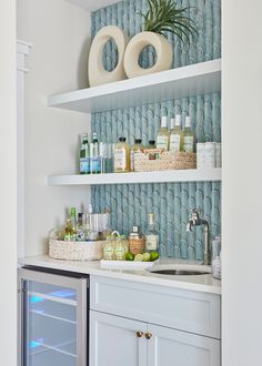 a white kitchen with blue wallpaper and shelves filled with bottles, soaps, and other personal care items