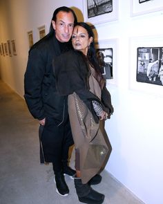 a man and woman standing next to each other in front of pictures on the wall