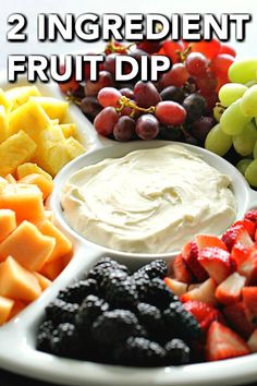 a white plate topped with fruit and dip surrounded by grapes, strawberries, pineapples