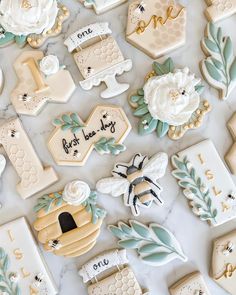 some decorated cookies are laying on a white counter top with flowers and leaves around them