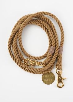 a brown rope with a gold metal hook and a brass plated charm on it