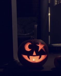 a carved pumpkin sitting on top of a floor in front of a door at night