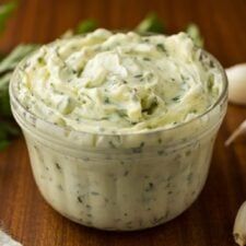 a small glass bowl filled with dip next to garlic