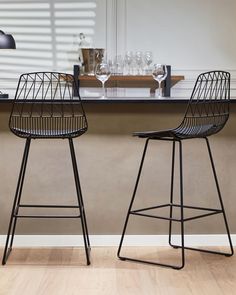 two black bar stools sitting on top of a hard wood floor next to a counter