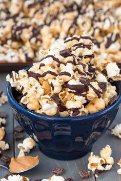 a blue bowl filled with chocolate popcorn and marshmallows on top of a wooden table