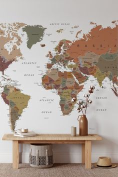 a large map of the world on a wall in a living room with a table and vase