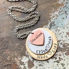 "Custom mothers necklace for grandma or mom with stamped kids names. 1 1/4\" handstamped solid brass tag 1\" solid silver alkeme disc 5/8\" solid copper heart charm. All pieces have a brushed satin finish and beveled edge. Stamped with your choice of names on copper heart (up to 7 letters). Gold and Silver discs stamped with names and hearts in between (up to 12 letters on each) or hearts on each side if there is only one name or you indicate they are first/middle names. Hangs from a .925 sterli Hand Stamped Round Disc Jewelry For Mom, Hand Stamped Round Disc Jewelry For Mother's Day, Adjustable Hand Stamped Charm Necklace As Gift For Mom, Mother's Day Hand Stamped Round Disc Jewelry, Adjustable Hand Stamped Charm Necklace For Mom, Stamped Round Pendant Charm Necklace For Mom, Hand Stamped Round Pendant Charm Necklace For Mom, Adjustable Stamped Charm Necklace For Personalized Gift, Hand Stamped Round Disc Necklaces For Mother's Day