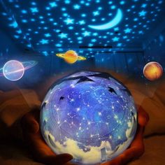 a person holding a glowing ball in their hand with stars and planets on the ceiling