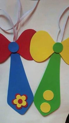 three wooden tags with different colors and designs hanging from a white ribbon on a table