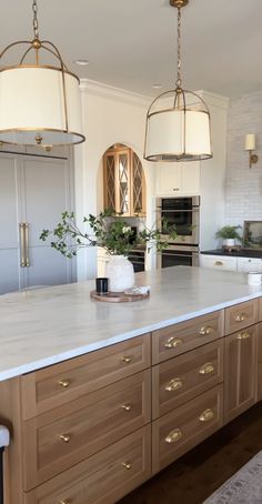 a large kitchen with an island in the middle and two pendant lights hanging from the ceiling