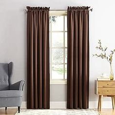 a living room filled with furniture and a large window covered in brown drapes