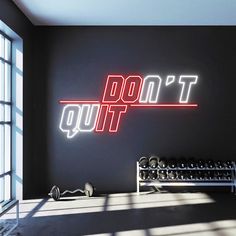 a gym room with a neon sign that says don't quit on the wall