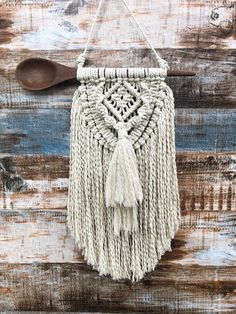 a macrame bag hanging on a wooden wall with a spoon in the background