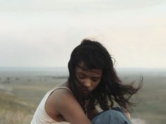 a woman sitting on top of a white horse next to a lush green field and sky