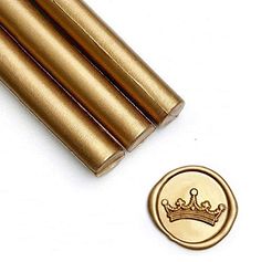 three gold colored metal rods with a crown on the top and a small coin next to them