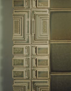 the wall is made up of squares and rectangles in shades of brown, beige and green