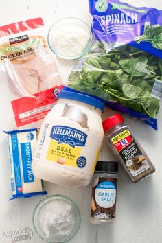 ingredients to make spinach salad laid out on a white surface, including milk, eggs, cheese and other items