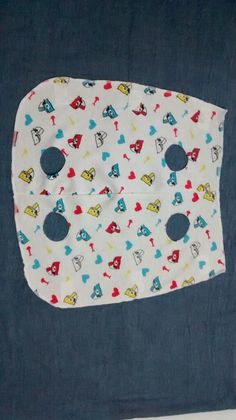 a baby bib with blue and red designs on it, hanging from a wall