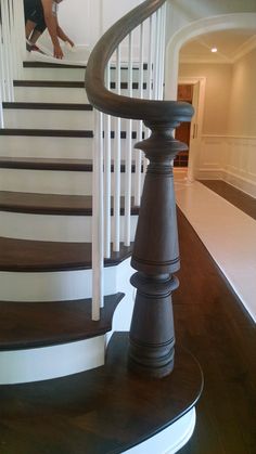 a spiral staircase with wooden handrails and white railing on the top floor in a house