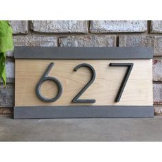 a wooden house number sign with the number sixty seven on it's front and side