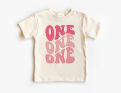 Retro First Birthday Toddler Shirt - Girls Pink Groovy 1ST Birthday Kid's Tee - One Birthday Party Theme - Boho Natural Toddler & Youth Tee If you love super soft, lightweight, extremely comfy shirts and baby bodysuits then you will absolutely love our unisex kids shirts and baby bodysuits! These shirts are hand printed with a professional garment printer for a soft, durable, long lasting, printed graphic using high quality water based inks. * The printed design is very soft to the touch due to Pink Birthday Shirt For Summer, Pink Summer Birthday Shirt, Pink Crew Neck T-shirt For First Birthday, Pink Crew Neck Top For First Birthday, Pink Number Print T-shirt For Birthday, Pink Short Sleeve T-shirt With Number Print, Pink Tops With Letter Print For First Birthday, Playful Pink Top For First Birthday, Playful Pink Tops For First Birthday