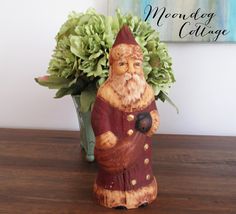 a gnome figurine sitting on top of a wooden table next to a potted plant