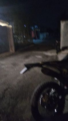 a dirt bike parked on the side of a road at night with its lights on