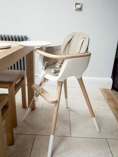 a baby's high chair sitting on top of a tiled floor next to a table