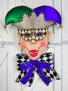 a close up of a mask on a white door with purple, green and blue colors