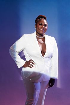 a woman in a white suit posing for the camera with her hands on her hips