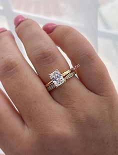 a woman's hand with two wedding rings on top of her finger and the ring is