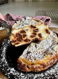 powdered sugar covered pastries sit on a black plate