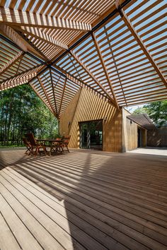 a wooden deck with chairs under a pergolated roof