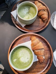 two plates with croissants on them and a cup of green liquid in the middle