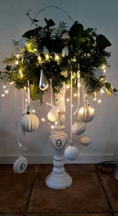 a white vase filled with christmas ornaments and greenery on top of a wooden table