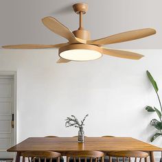 a wooden table with four chairs and a ceiling fan