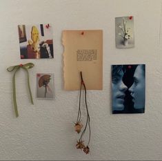 a white wall covered in pictures and magnets next to a string with a bow on it