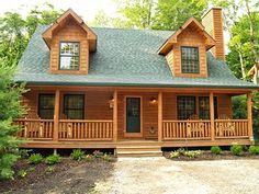 a log cabin with porch and wraparound deck in front of the house surrounded by trees