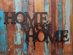 a metal sign that says home is where the heart is on a wooden background with rusted paint