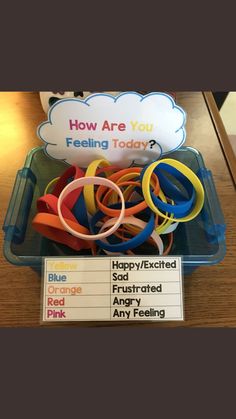 a plastic container filled with lots of different colored rubber bands and an information sign that says how are you feeling today?