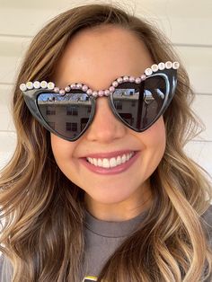 a close up of a person wearing sunglasses with pearls on the side and one eye