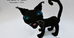 a crocheted black cat with blue eyes and whiskers on its tail