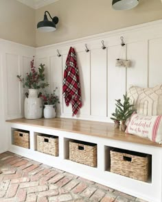 a white bench with baskets on it next to a coat rack and christmas tree in the corner